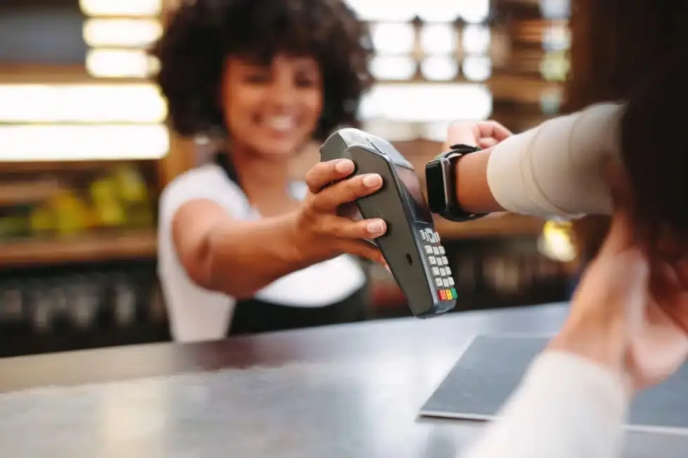 Customer making a contactless payment using a smartwatch at a store counter.