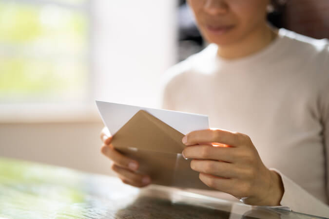 A woman opening a letter, representing how you can reach customers through resident marketing lists.