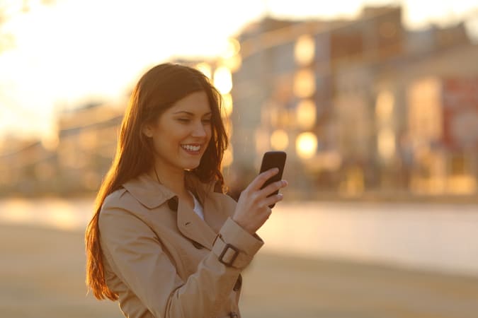 A woman on her phone outside, representing how Deep Sync's data-driven digital marketing services can help you reach your audience wherever they are.