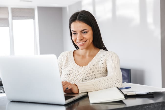 A happy woman on a computer, representing a potential customer you can reach through email acquisition marketing