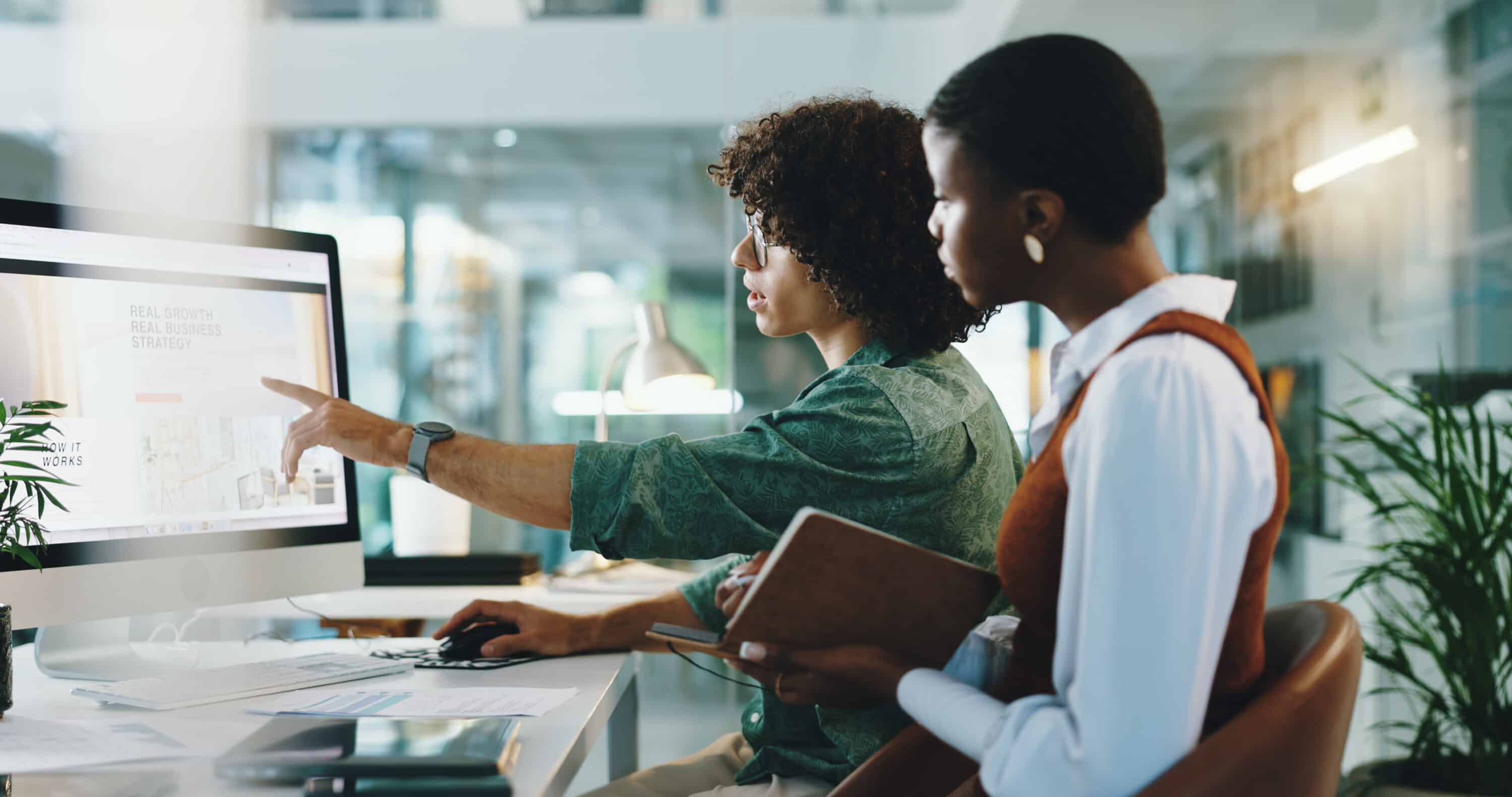 two co-workers sitting at a desk collaborating on a marketing project together